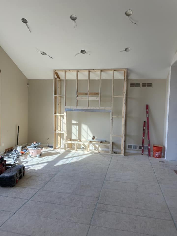 Framing stage of new fireplace surround with rough lumber stud wall and recessed firebox opening